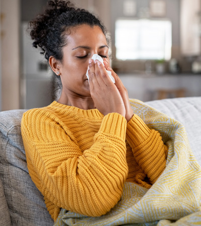 A cold infected woman holding her nose with an hanky