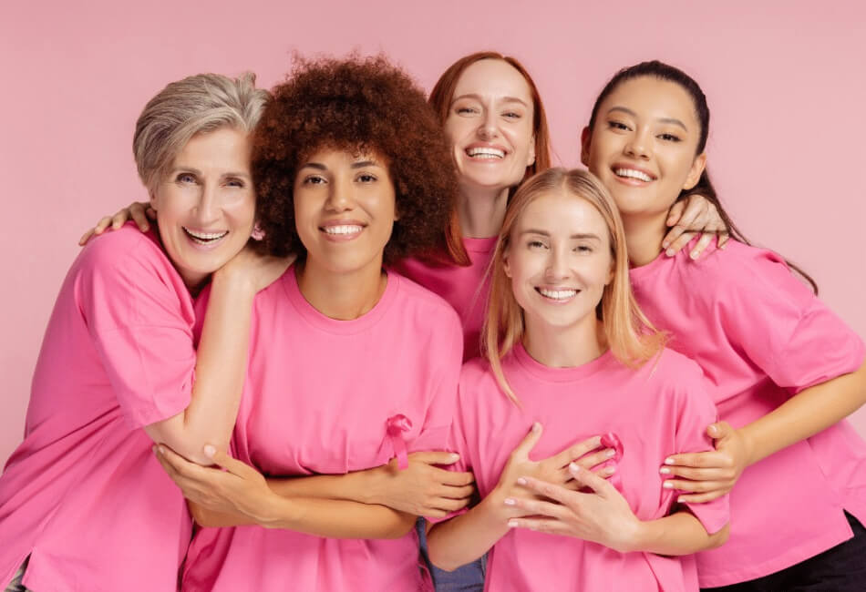 5 smiling women wearing pink tshirts