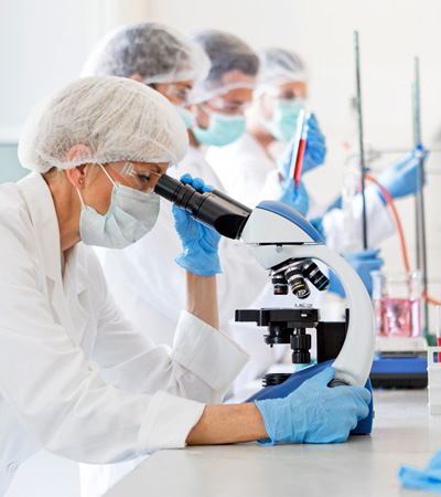 A lab technician checking something using microscope in a lab with other technicians