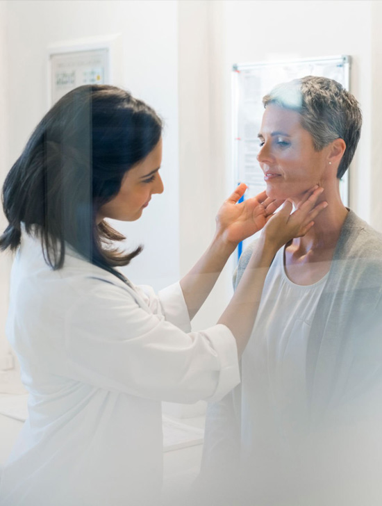 Image of a lady doctor touching and checking her lady patient's neck